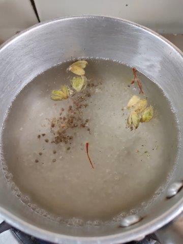 adding cardamom and saffron in syrup for kesari halwa