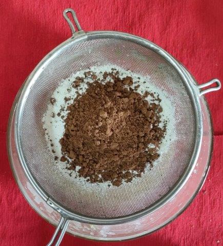 sieve dry ingredients-flour, cocoa powder, baking soda for chocolate muffin