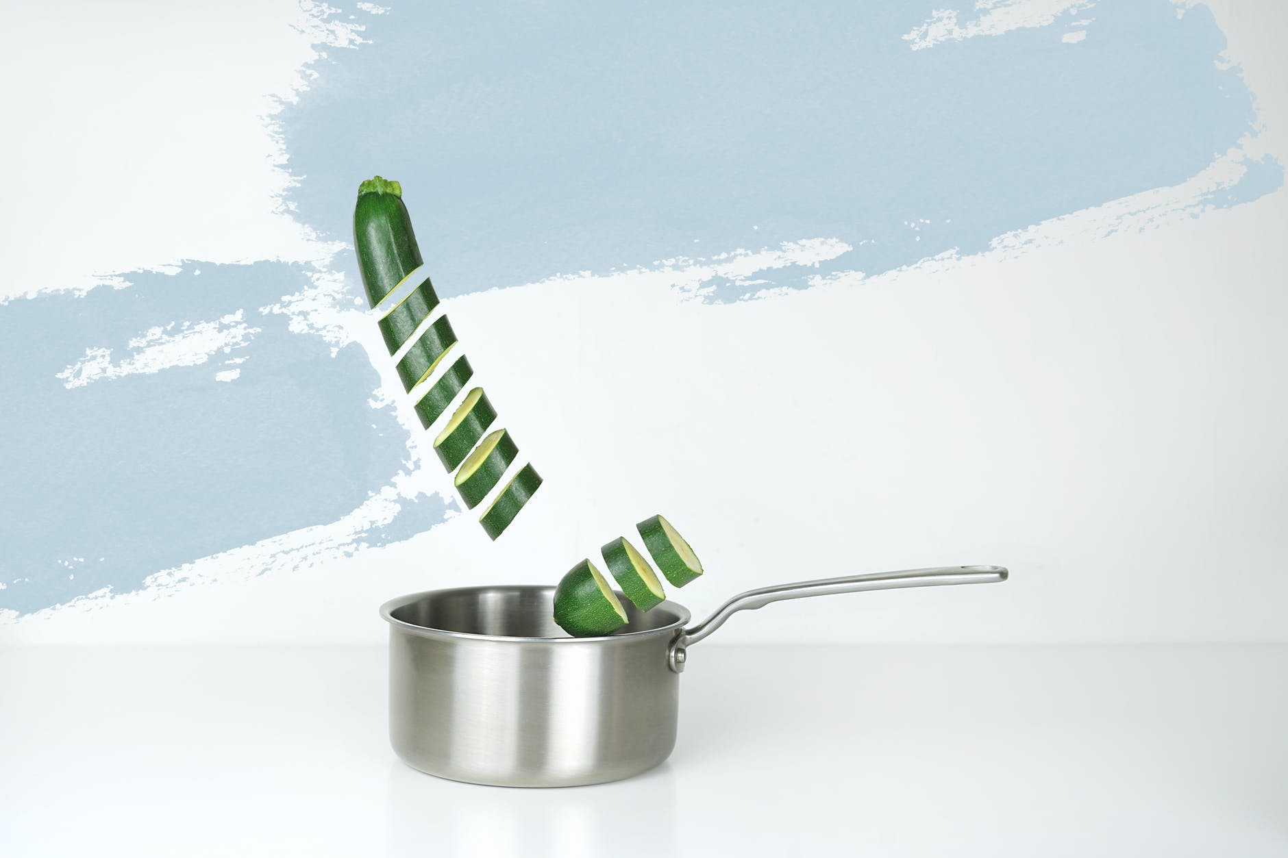gray stainless steel sauce pan and green cucumber illustration