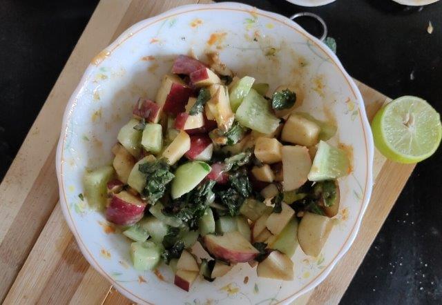 mixing the chopped veggies and dressing for apple cucumber salad.