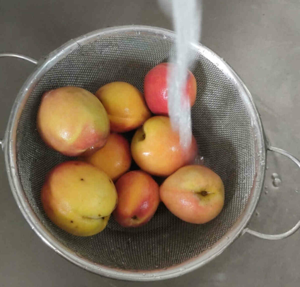 washing fresh peaches under tap water