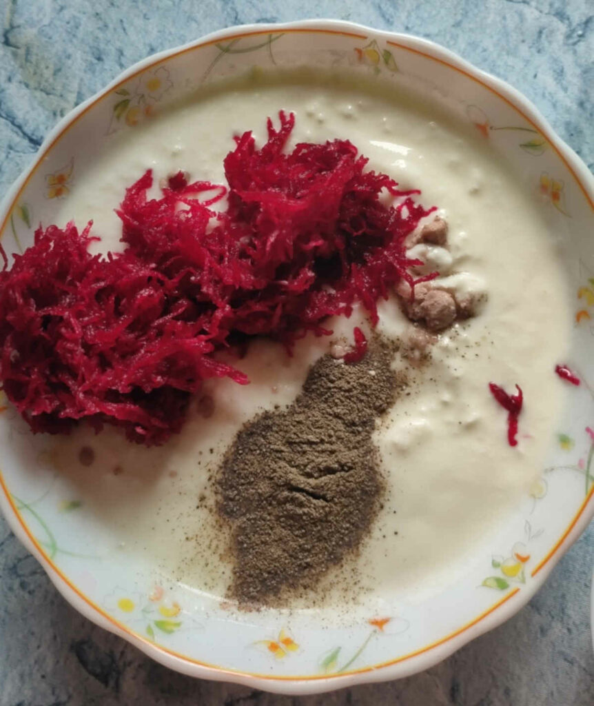 in a bowl of curd, add grated beet with salt and pepper for beet raita