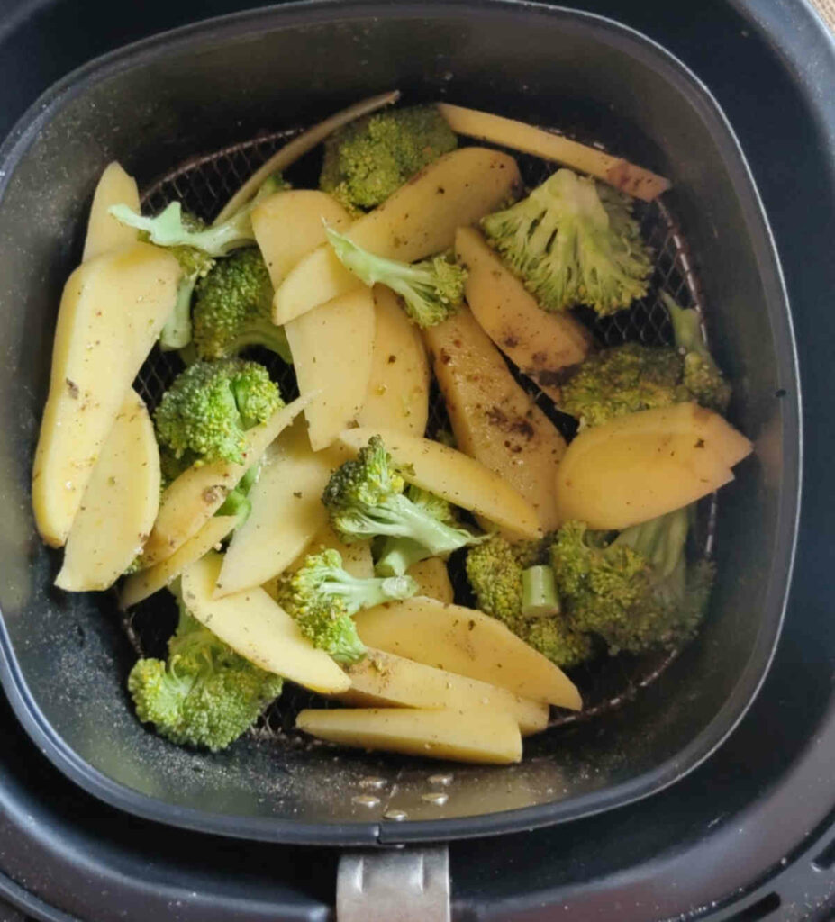 place the spices oil mixed broccoli and potatoes in air fryer basket