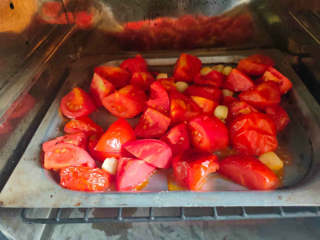 placed the baking tray with tomatoes garlic for roasting